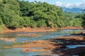 Waterway in mountain with cloudy sky and forest in background