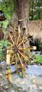 A waterwheel made of bamboo that is rotating due to the flow of water in the pond splashing the water.