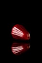 Watery rose apple on a black reflective background