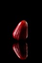 Watery rose apple on a black reflective background