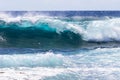 Wave breaking offshore in Hawaii; foam in foreground. Blue ocean, sky, clouds in background. Royalty Free Stock Photo