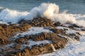 Wave breaking on rocks; spray in the air; foam, water draining back to the ocean. Royalty Free Stock Photo