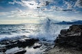 A wave breaks on a rock on a sunny day.