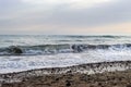 a wave breaks on the shore of the beach. on the shore there are stones