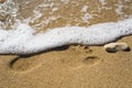 Wave covering footprint on a beach sand Royalty Free Stock Photo