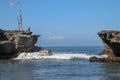 Wave crashing onshore at low tide in Bali, Indonesia. Water cascading over stone, feeding tidal pool. Wave breaking on rock during