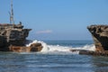 Wave crashing onshore at low tide in Bali, Indonesia. Water cascading over stone, feeding tidal pool. Wave breaking on rock during