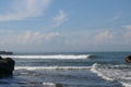 Wave crashing onshore at low tide in Bali, Indonesia. Water cascading over stone, feeding tidal pool. Wave breaking on rock during