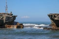 Wave crashing onshore at low tide in Bali, Indonesia. Water cascading over stone, feeding tidal pool. Wave breaking on rock during