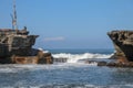 Wave crashing onshore at low tide in Bali, Indonesia. Water cascading over stone, feeding tidal pool. Wave breaking on rock during