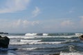 Wave crashing onshore at low tide in Bali, Indonesia. Water cascading over stone, feeding tidal pool. Wave breaking on rock during