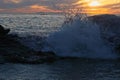 Wave crashing over rocks at sunset Royalty Free Stock Photo