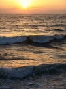 Wave crashing in the sea, at sunset with water drops splashing and flying in the air and warm orange color from the sun