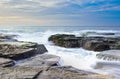 The wave flows over weathered rocks and boulders at North Narrabeen Royalty Free Stock Photo