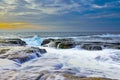 The wave flows over weathered rocks and boulders at North Narrabeen