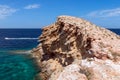 A wave frozen in stone in the emerald sea with speed boat. Cape Punta Galera. Ibiza, Balearic Islands, Spain