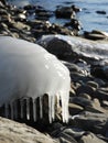 Wave ice icicles on lakeshore rocks