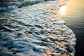 Wave of the ocean sea on the sand beach at the sunset light.