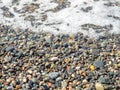 Wave on a pebbly shore. Sea foam. Beautiful pebble beach. Close-up of the coastline Royalty Free Stock Photo