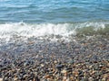 Wave on a pebbly shore. Sea foam. Beautiful pebble beach. Close-up of the coastline Royalty Free Stock Photo