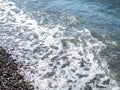 Wave on a pebbly shore. Sea foam. Beautiful pebble beach. Close-up of the coastline Royalty Free Stock Photo