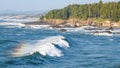 Wave rolls towards tree lined shore on the Oregon Coast