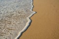 Wave of the sea entering the sand of the beach forming foam, contrast of white and beige. Macro photography Royalty Free Stock Photo