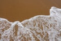 Wave of the sea with white foam against the background of a sandy beach