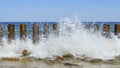 Wave on the seashore crashes on wooden breakwaters Royalty Free Stock Photo