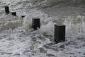 Wave slashing on wooden posts. Royalty Free Stock Photo