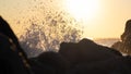 Wave splashing against rock on the shore at sunset, spraying water droplets into the air Royalty Free Stock Photo