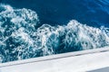 Wave trace with white foam on a water surface behind of fast moving yacht