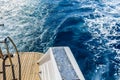 Wave trace with white foam on a water surface behind of fast moving yacht