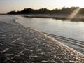 Waves from a boat roll onto the canal embankment at sunset Royalty Free Stock Photo