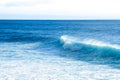 Waves braking close to the beach shore with blue turquoise ocean water and resulting white foam