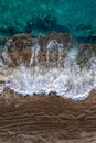 Waves breaking on brown cliff rocks with rising tide, drone shot directly above