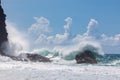 Waves, breaking on rocky, pristine shoreline under blue sky with Royalty Free Stock Photo