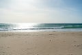 Waves breaking on a sandy beach spray white water and sand in foreground