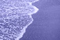 Waves breaking on shore of the sea. closeup of sea foam on wet sand. photo toned in the color of the year very peri