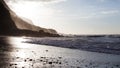 Waves breaking on the shore of a Tenerife beach with back light of the oncoming sunset. Royalty Free Stock Photo