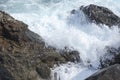 The waves breaking on a stony beach, forming a spray. Wave and splashes on beach. Waves crashing onto rocks.