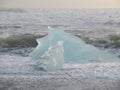 The waves clashing a huge blue iceberg on Black Sand Beach