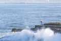 Waves crashing around surf fisherman on rocky shore in Ocean Beach Royalty Free Stock Photo