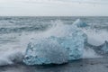 Waves crash into glacier ice washed ashore on a black sand beach. Diamond Beach, Iceland Royalty Free Stock Photo