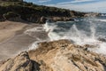 Waves crash onto a small sandy cove near Calvi in Corsica