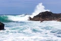 Waves crash onto volcanic rocks.