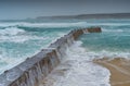 Waves crash over the curving sea wall. Sennen Harbour, Cornwall. Royalty Free Stock Photo