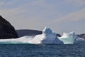 Waves crashing against icebergs stranded next to rugged coastline in bay outside St. John\'s