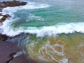 Waves crashing against the rocks at the beach on a cloudy day at Crescent Bay Beach