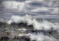 Waves crashing onto the rocky shoreline beneath a cloudy sky on the Isle of Skye.